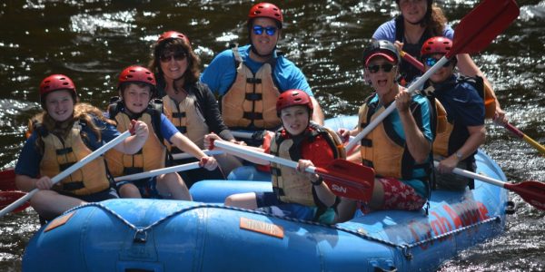 group of rafters floating on the river as they all pose for the camera