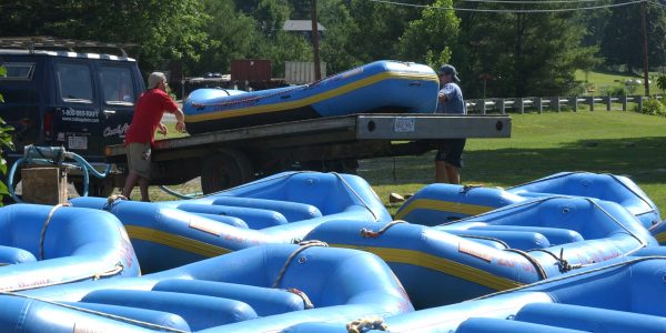 two men unloading rafts from a truck bed