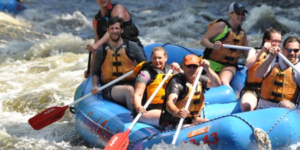 group of rafters paddling down river as they stare into the distance