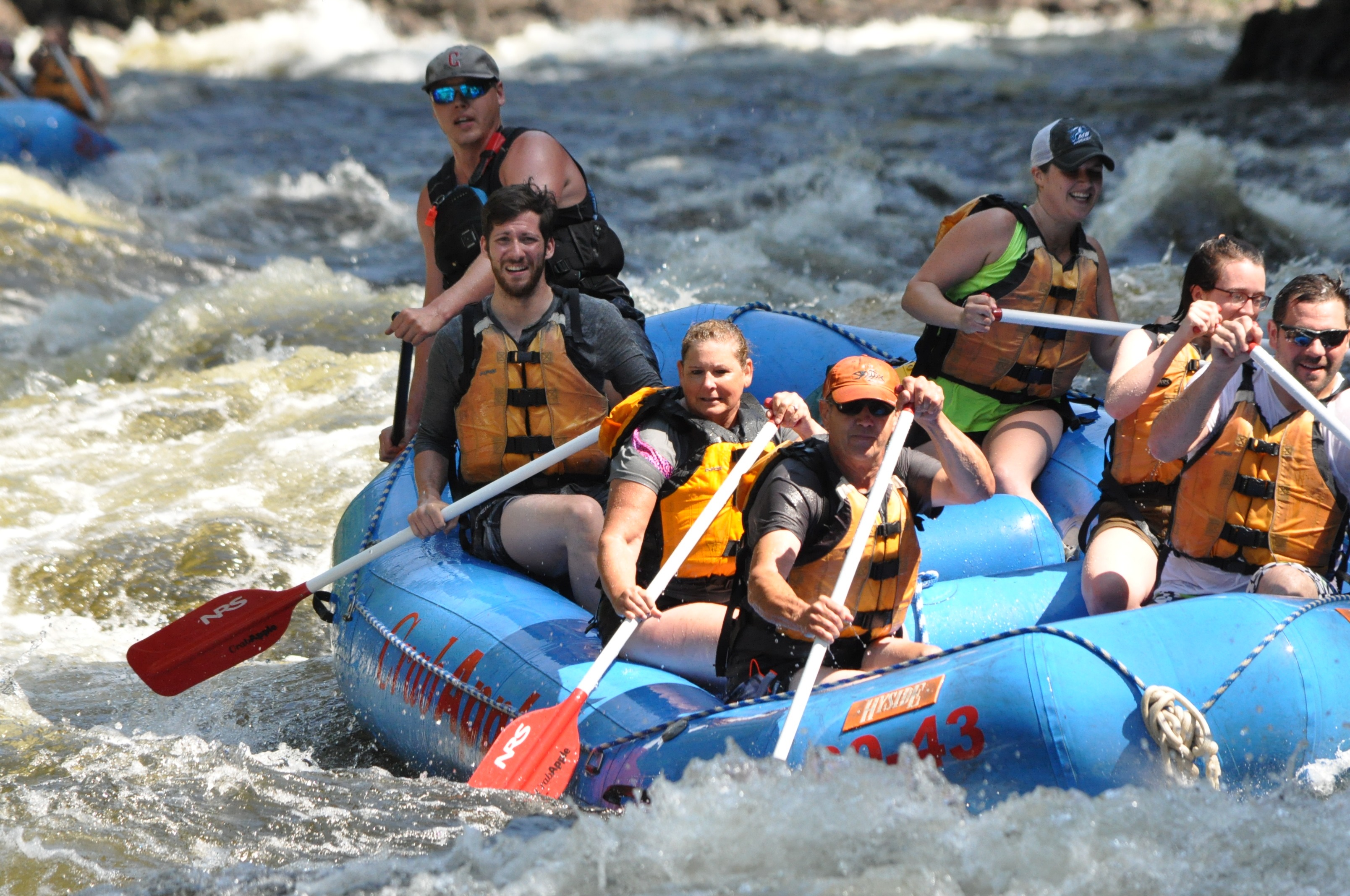 group of rafters paddling down river as they stare into the distance