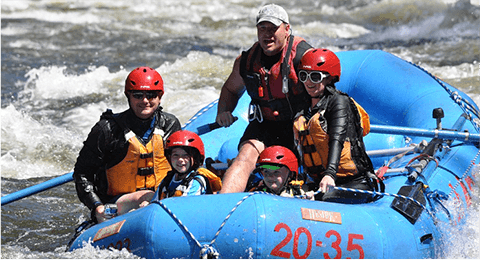 tour guide paddling in the back as parents and two kids sit on the raft smiling