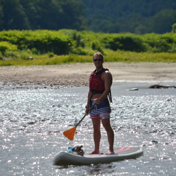 Vacationer near the shore on a stand-up paddle board.