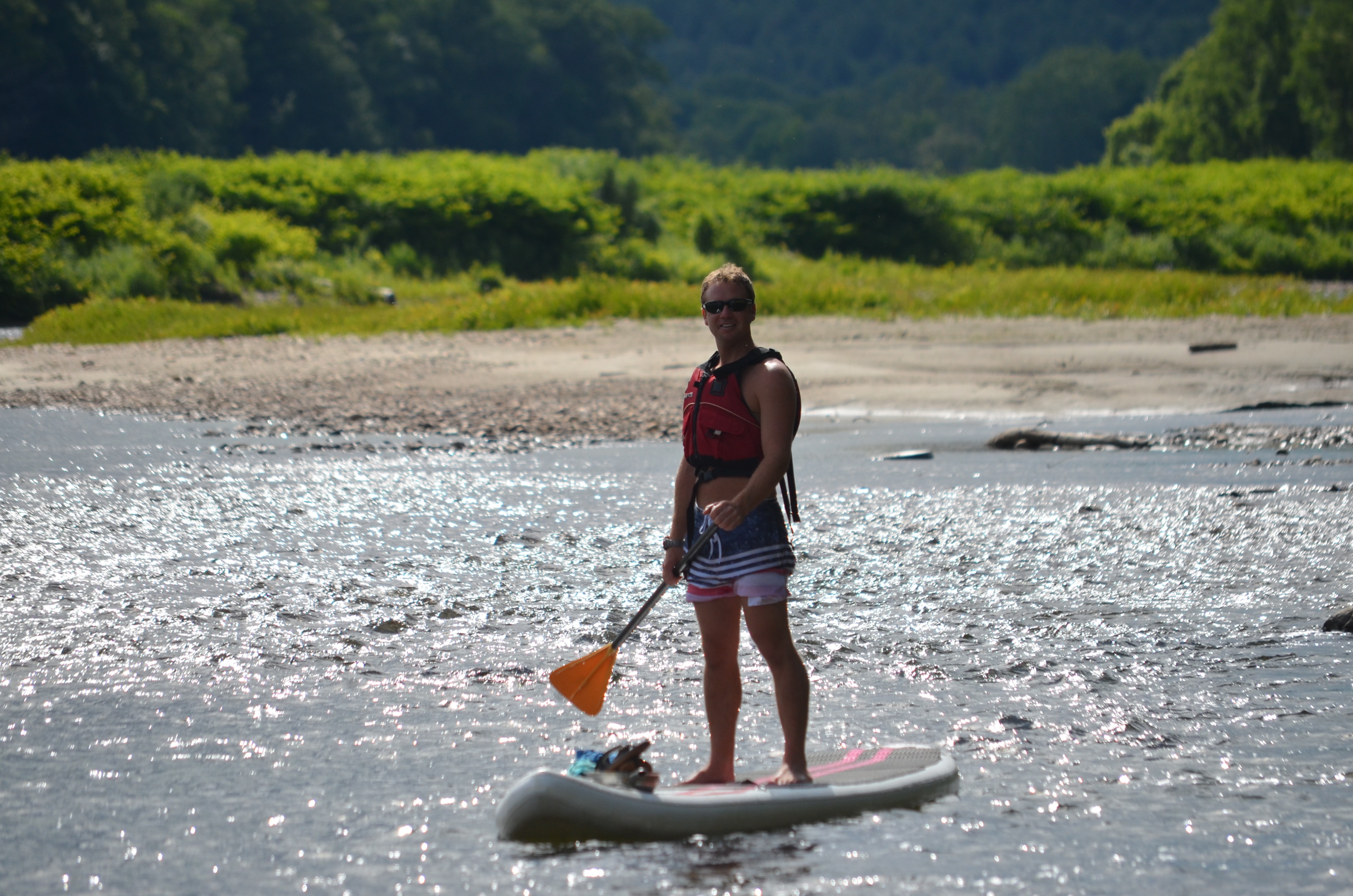 Vacationer near the shore on a stand-up paddle board.