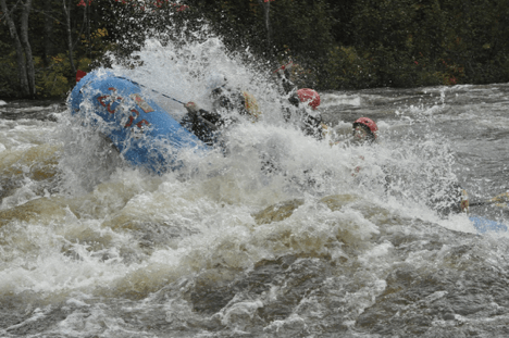 group of rafters getting flipped over by a large wave