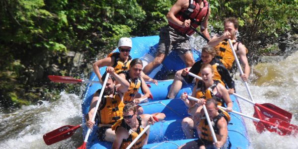 group of rafters going downhill as the back of the raft lifts in the air